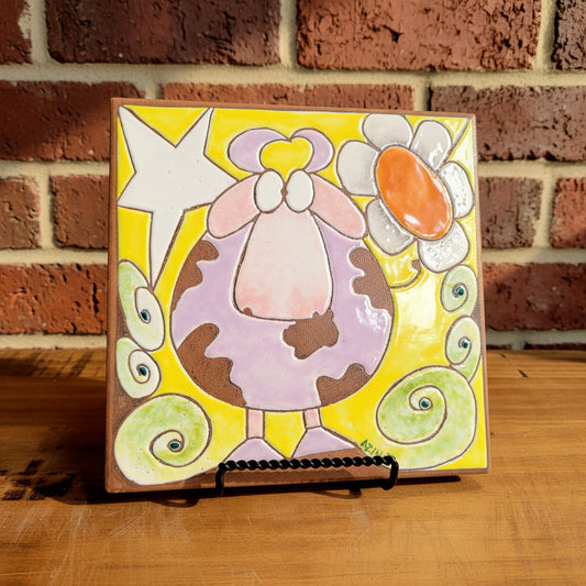 Colorful ceramic tile with a cartoonish cow design 